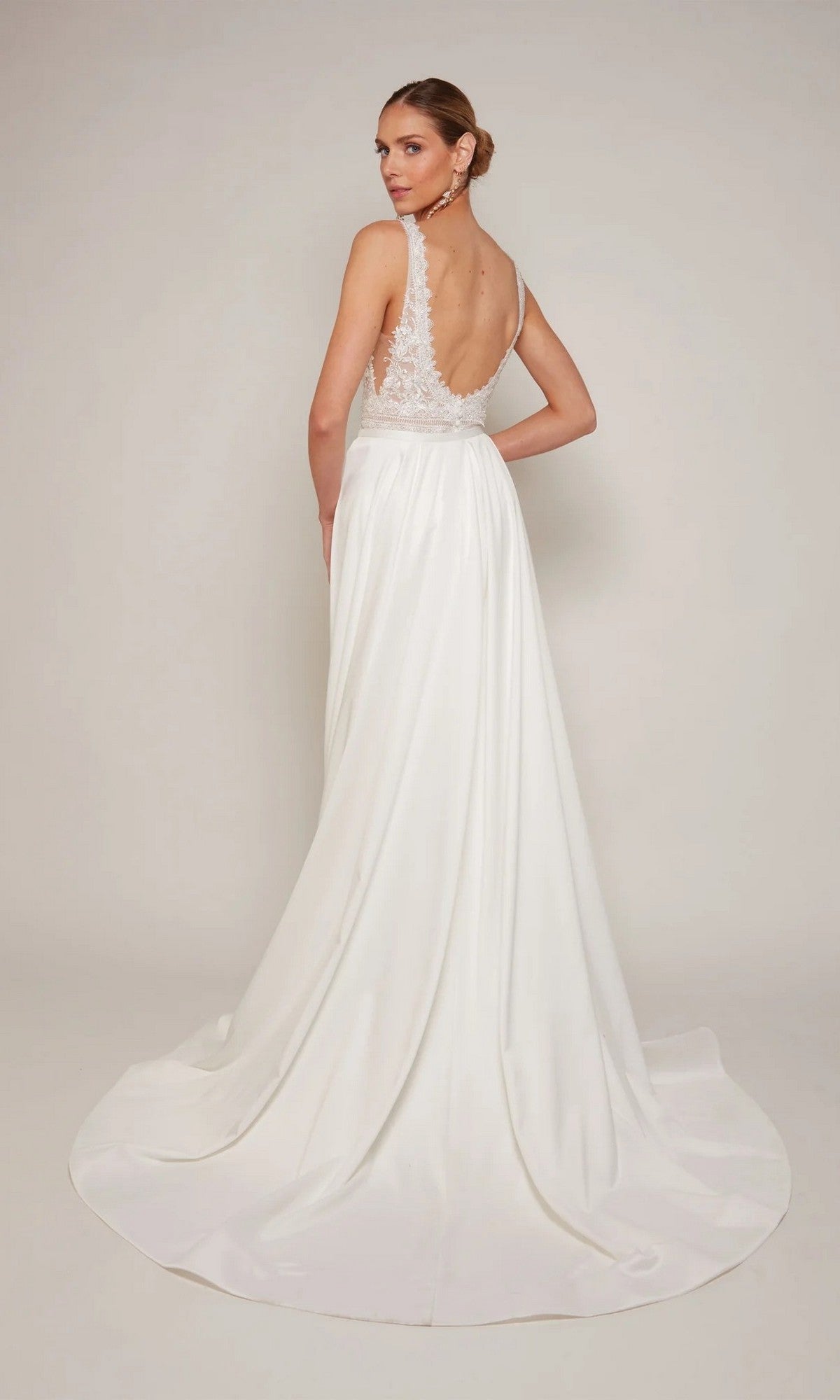 A woman faces away from the camera wearing the Alyce 7097, a long formal dress with a sleeveless sheath silhouette, low back, and delicate lace details.